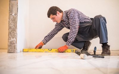 Home tile improvement - handyman with level laying down tile floor